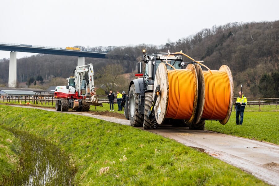 Layjet-Verlegeeinheit mit folgendem Bagger, der den wieder verfüllten Schlitzgraben statisch verdichtet, beim GigaGlasfaserausbau in der Saarner Ruhraue.