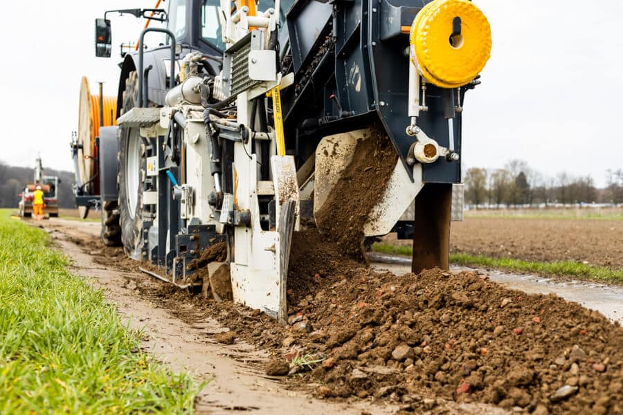 Detailaufnahme der sog. Layjet-Verlegeeinheit beim GigaGlasfaserausbau in der Saarner Ruhraue mit Fokus auf das automatische Wiederverfüllens des Schlitzgrabens
