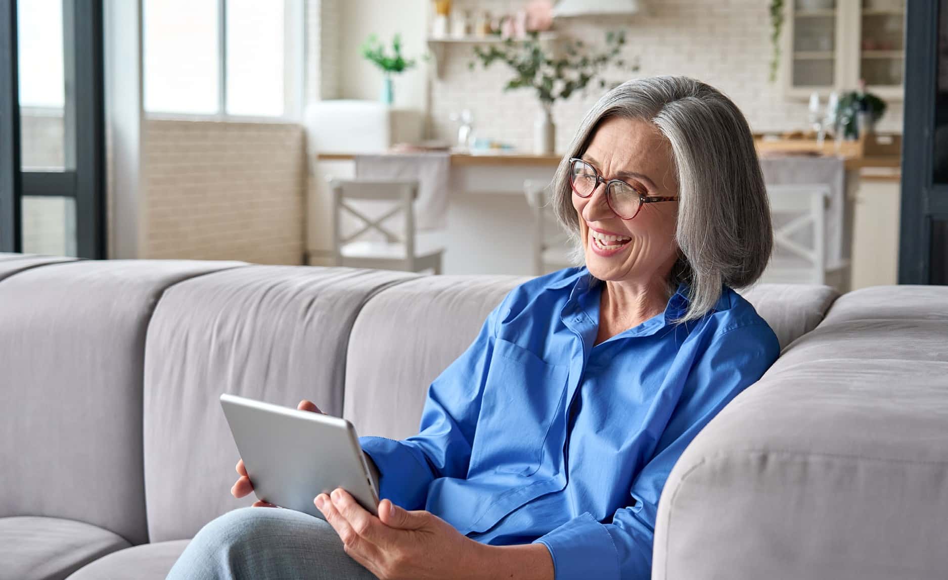 Energieversorger bequem von zu Hause wechseln Person sitzt entspannt auf dem Sofa und bedient ein Tablet – Symbol für den bequemen, digitalen Wechsel des Energieversorgers von zu Hause.