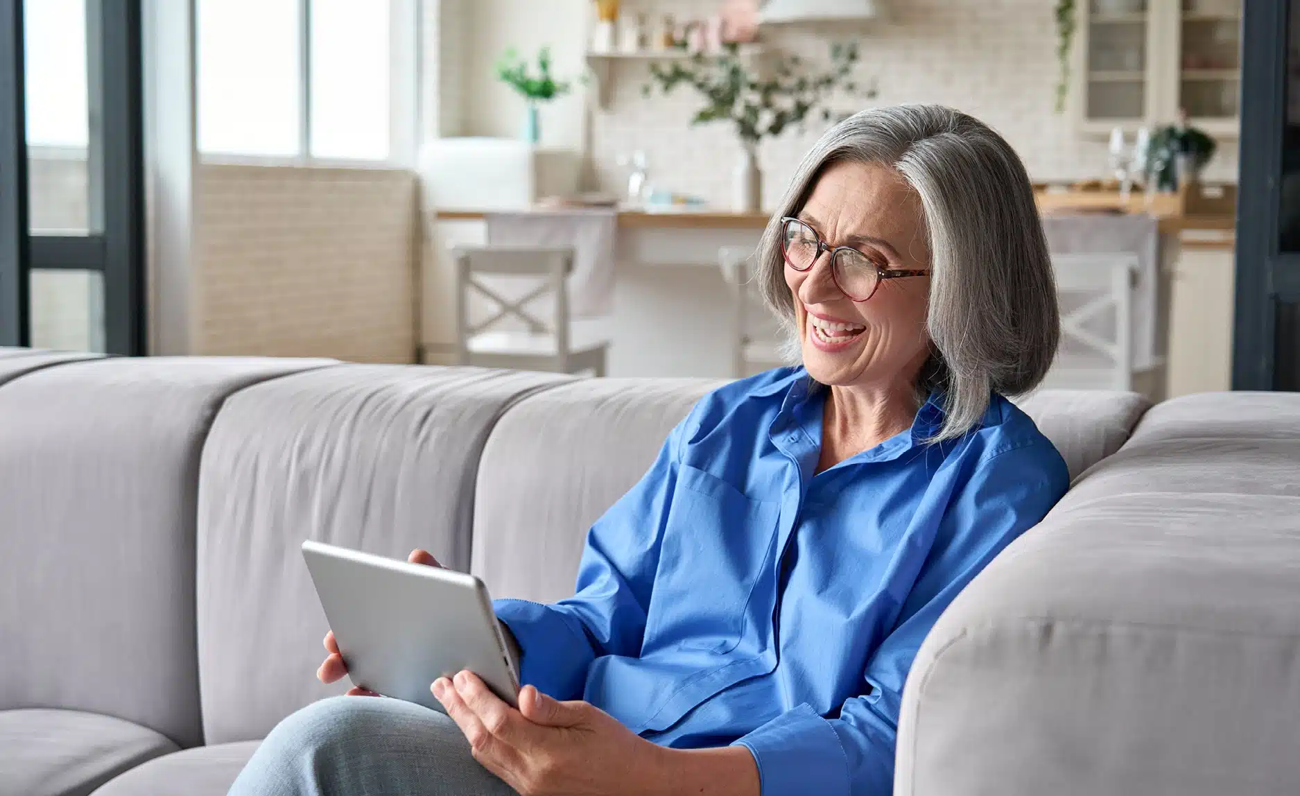 Energieversorger bequem von zu Hause wechseln Person sitzt entspannt auf dem Sofa und bedient ein Tablet – Symbol für den bequemen, digitalen Wechsel des Energieversorgers von zu Hause.