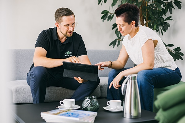 Ein medl-Mitarbeiter berät eine Kundin in ihrem Zuhause mithilfe eines Tablets – entdecke auch du den persönlichen Kundenservice von medl.