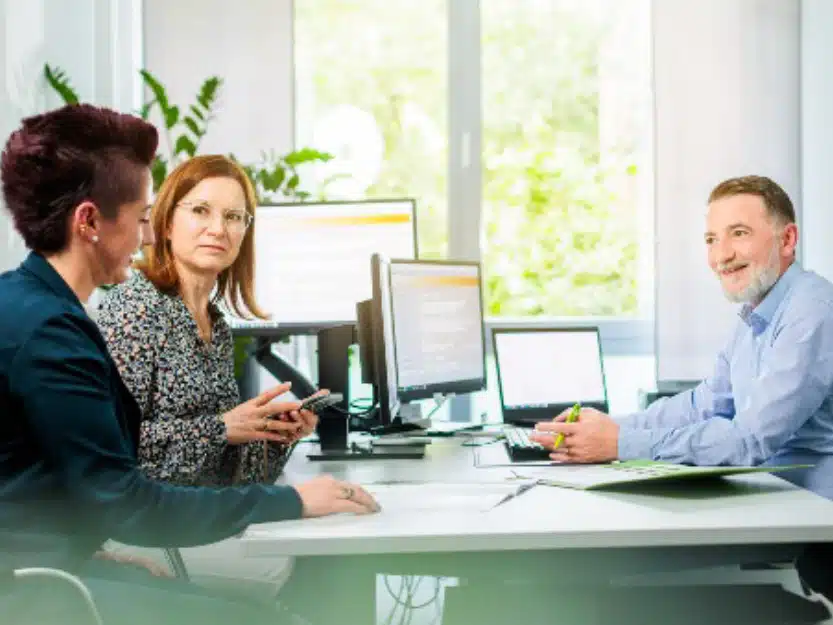medl Kundenberater im freundlichen Gespräch mit zwei Kundinnen im Kundenservice Mülheim.