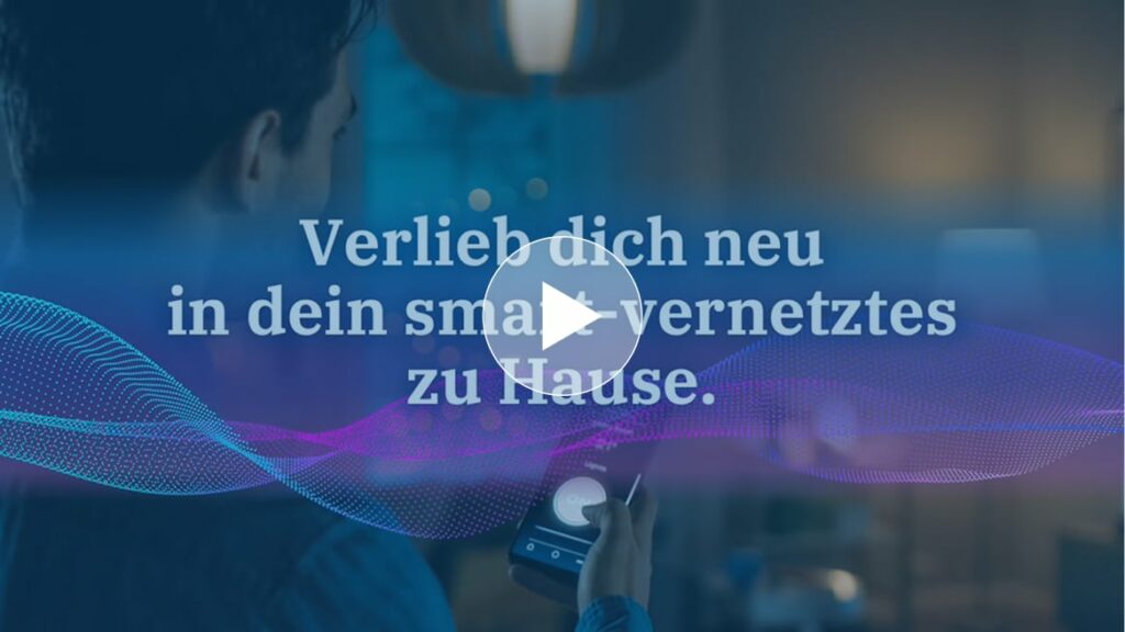 Videoteaser zu einem Smart-Home: Im Vordergrund hält eine Person ein Smartphone, im Hintergrund ein modern beleuchtetes Wohnzimmer. Darüber liegt ein Play-Button, im Bild steht der Text „erleb dich neu in dein smart-vernetztes zu Hause“ sowie eine farbige, wellenförmige Datenlinie.