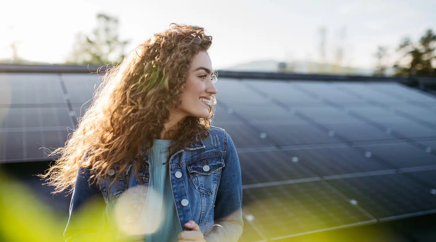 Lächelnde Frau vor einem Solardach – Symbol für das Sonnenstrom-Rundum-Paket von medl.